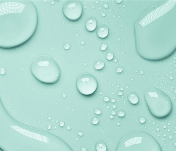 Water droplets on top of a mint green backdrop